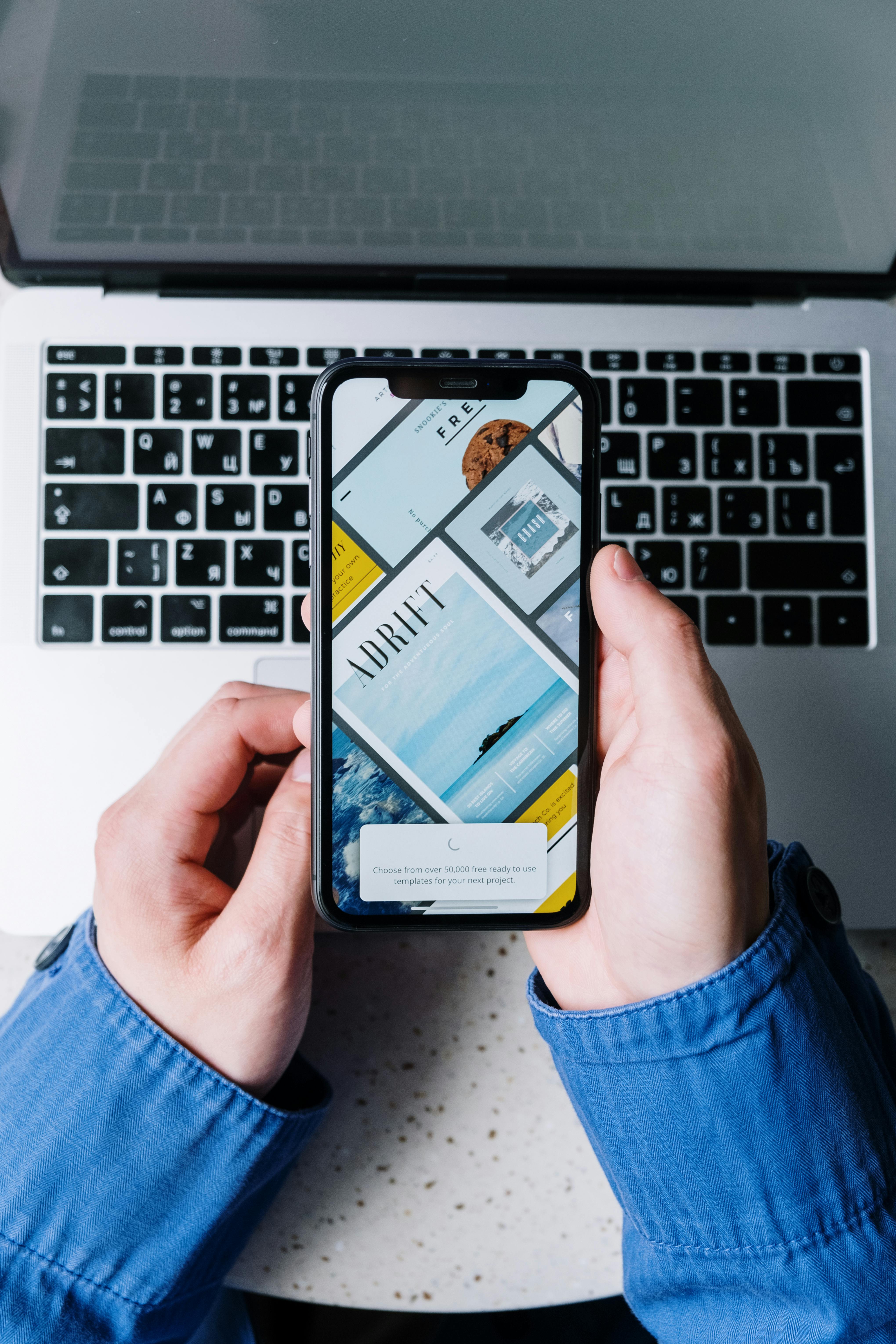 Mobile Suche und digitale Sichtbarkeit Person hält ein Smartphone über einem Laptop und nutzt eine digitale Such- oder Website-Oberfläche.